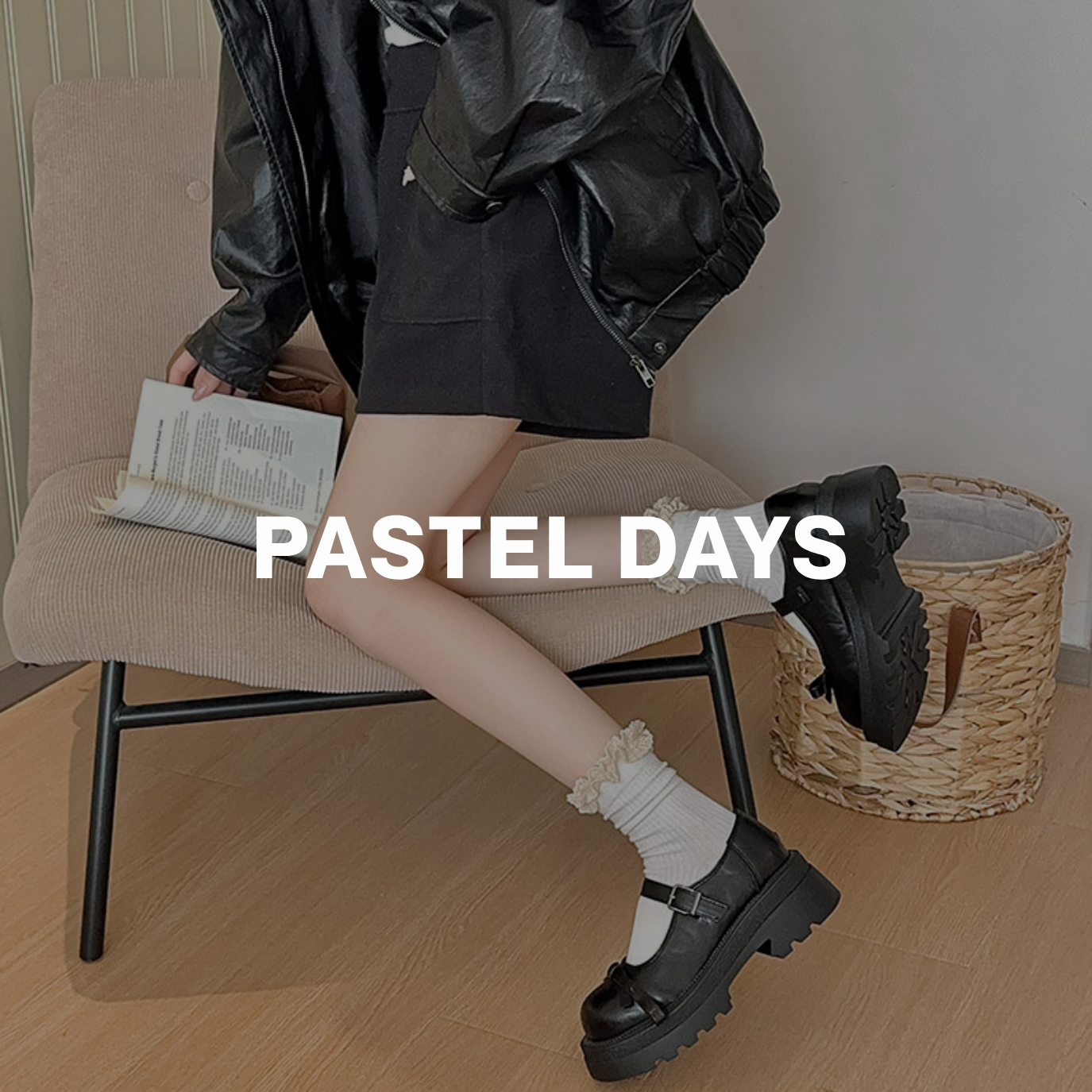 Model seated on a chair wearing white lace cuff socks and black Mary Jane shoes, styled with a black skirt and leather jacket — labeled Pastel Days.