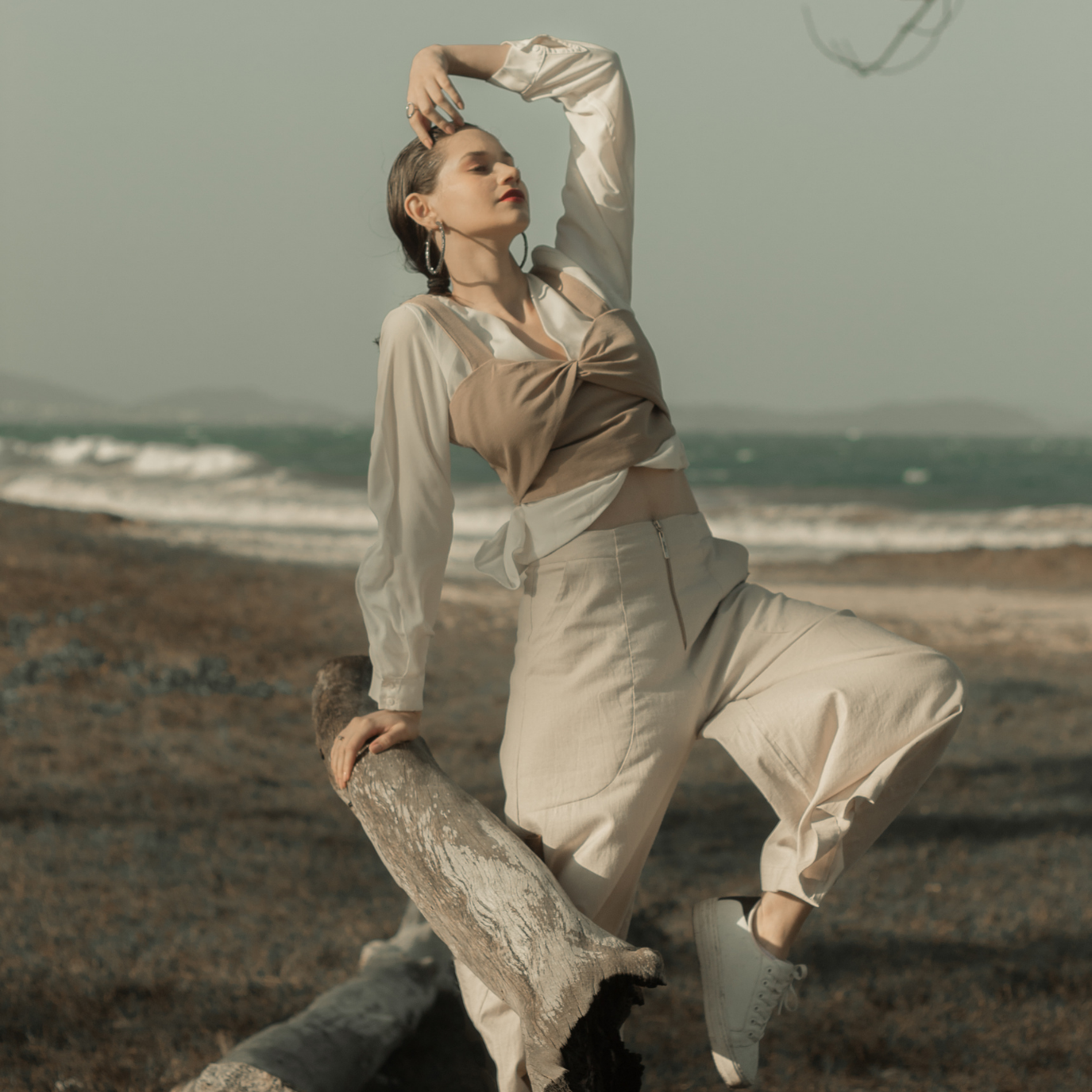 Editorial beachside shot of woman in neutral fashion — soft, earthy tones reflecting Y.loe’s calm and feminine brand aesthetic.