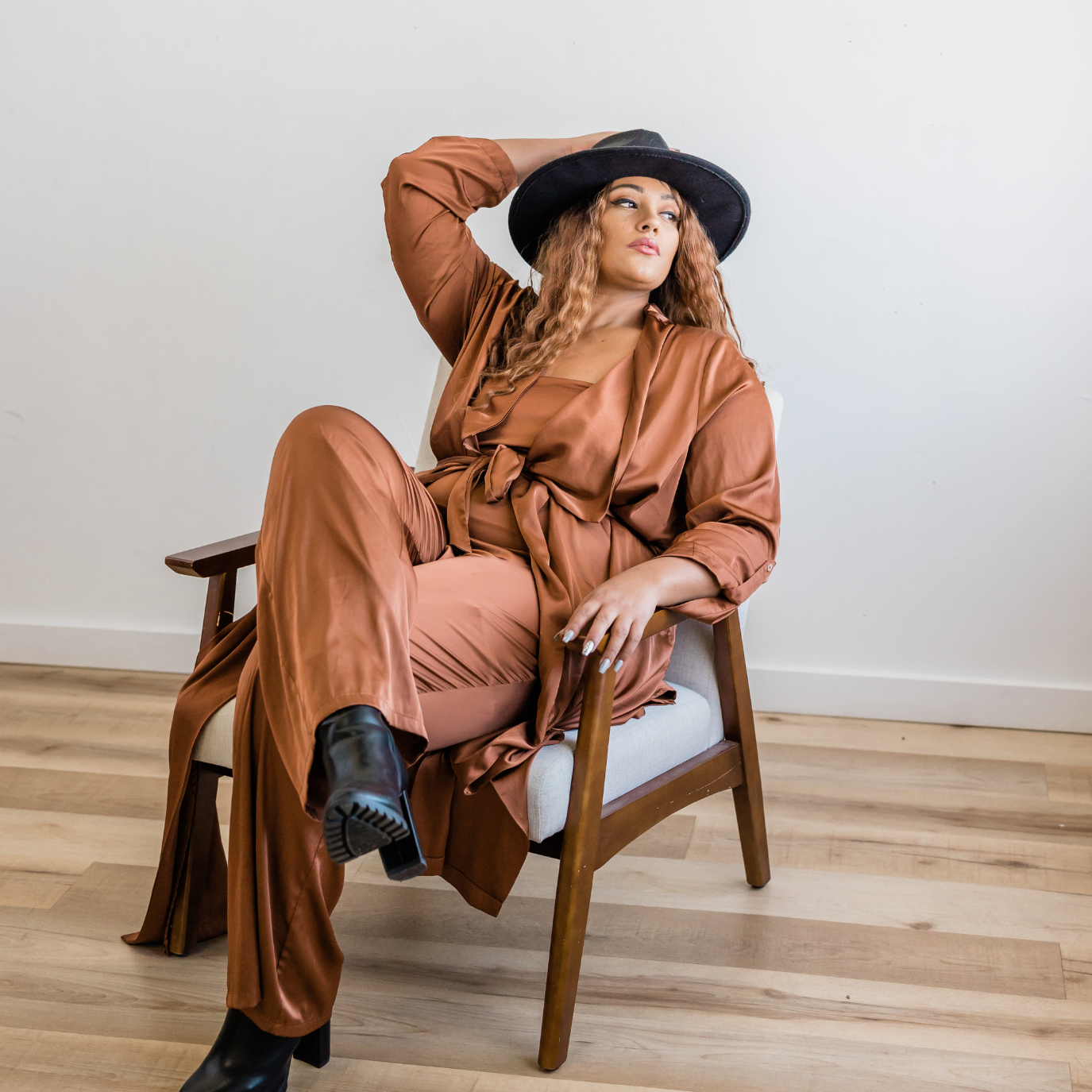 Empowered feminine look featuring a rust satin co-ord and wide-brim hat — modern softness and style reflected in Y.loe’s brand ethos.