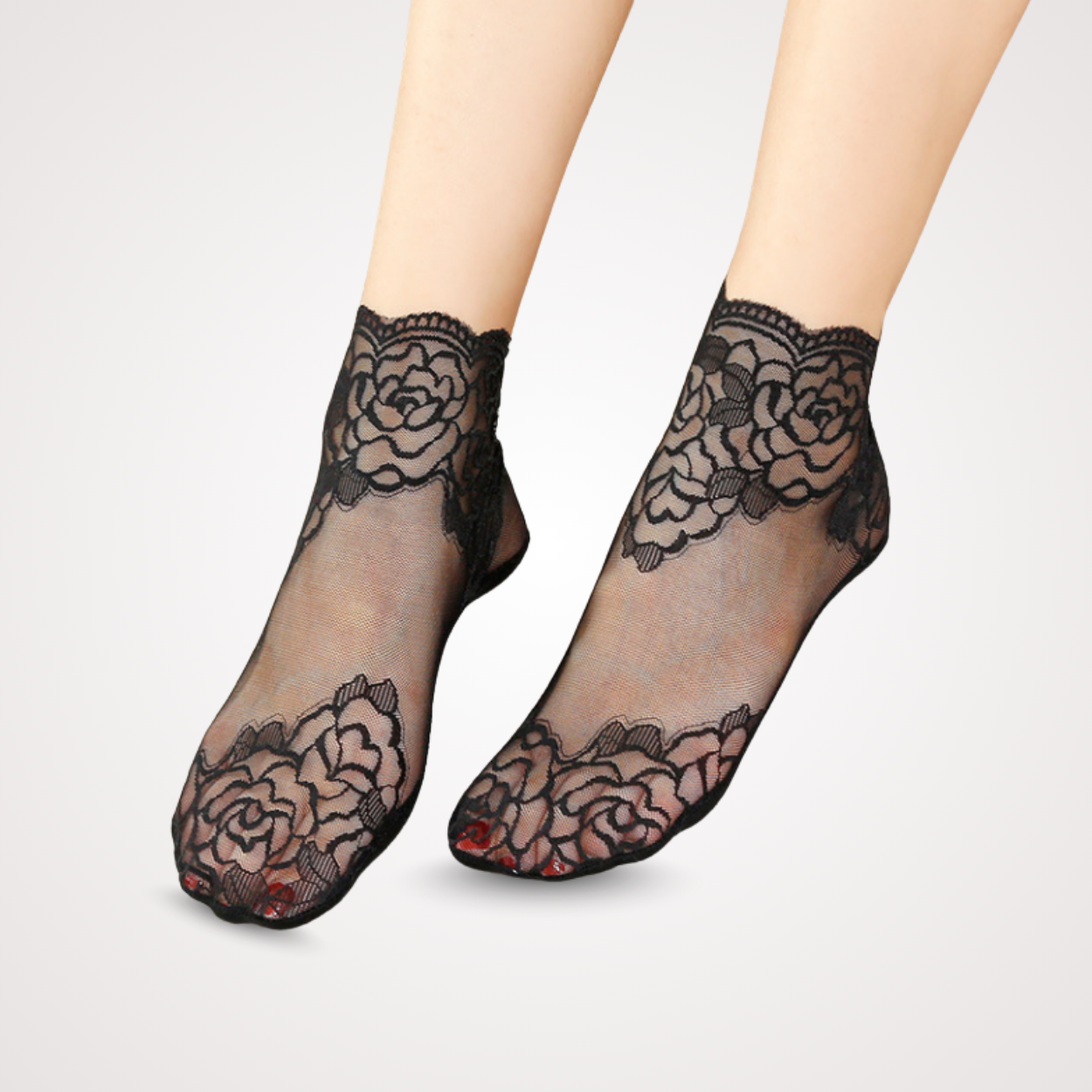 Feet wearing sheer black lace ankle socks with floral embroidery and scalloped cuffs, designed with anti-slip grip.