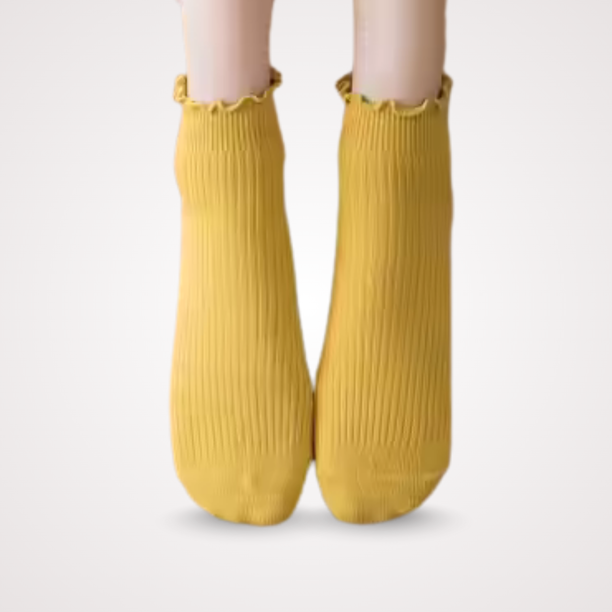 Feet wearing ribbed yellow ankle socks with delicate scalloped lace edge, styled for a bright and cheerful look.